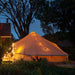 8 person bell tent Sibley 700 Ultimate Double Door set up in a backyard side view with lights making the tent glow
